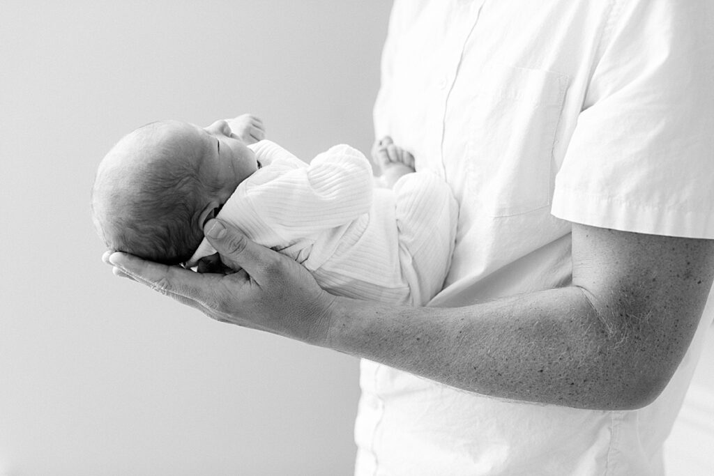 A black and white portrait of a father holding his newborn son in Indianapolis.