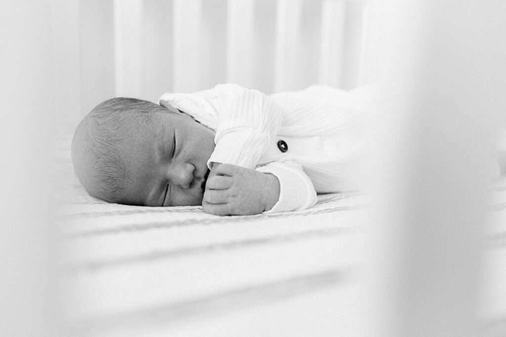 A black and white photo of a newborn baby boy lying in his crib by Indianapolis photographer Katelyn Ng
