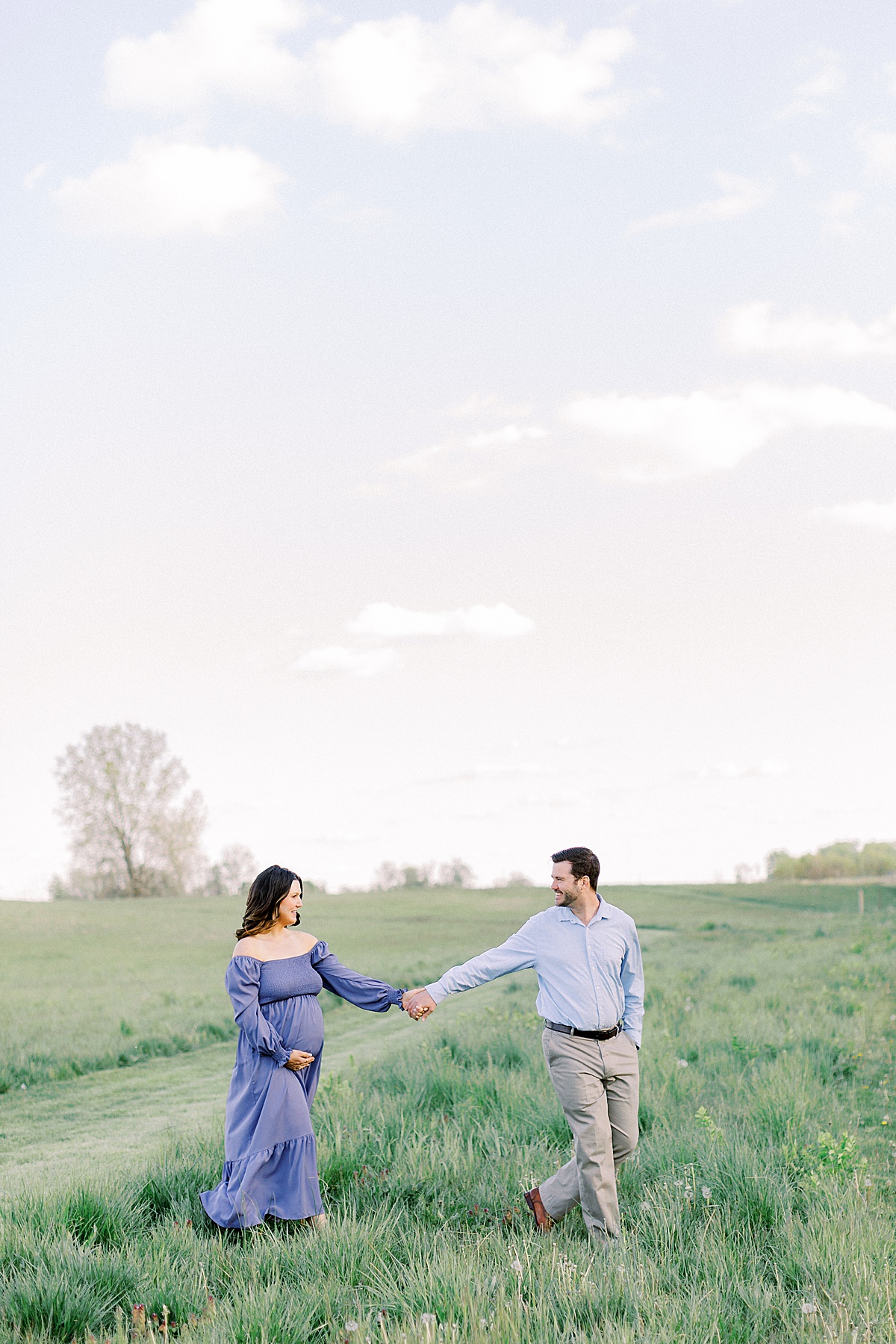 A couple walks hand in hand in an Indianapolis field.