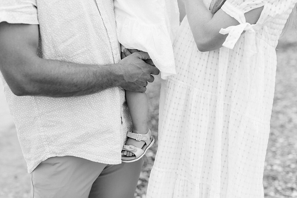 A black and white photo of mom and dad holding their little girl by Katelyn Ng Photography.