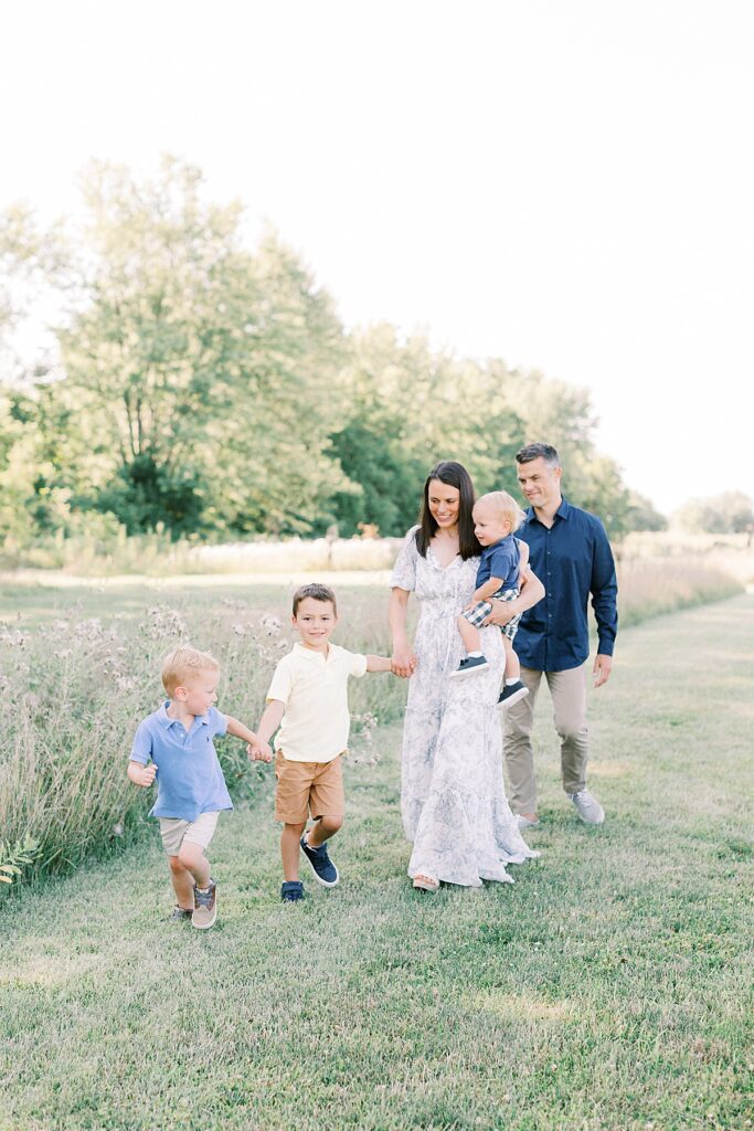 A greenwood Indiana family walks outdoors in a field in a photo by Greenwood Indiana family Photographer Katelyn Ng.