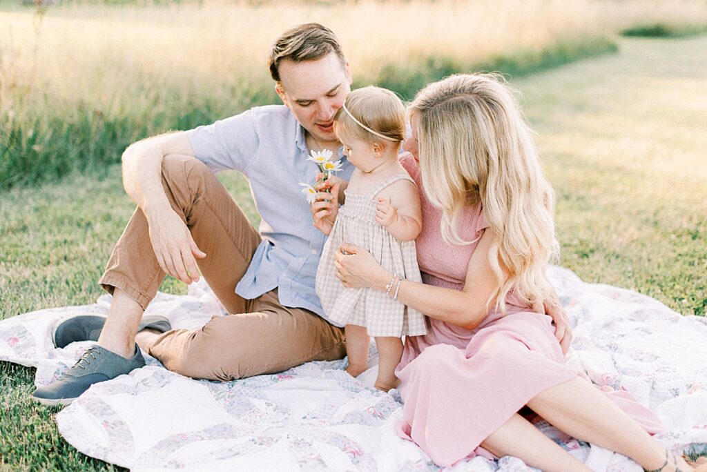 A family of three sits on a quilt in a photo by Indianapolis family photographer Katelyn Ng Photography.