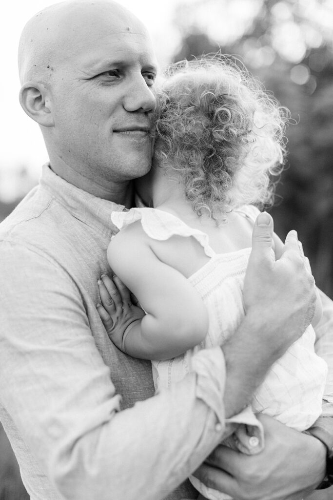 A father embraces his little daughter in a black and white photo by Katelyn Ng Photography.