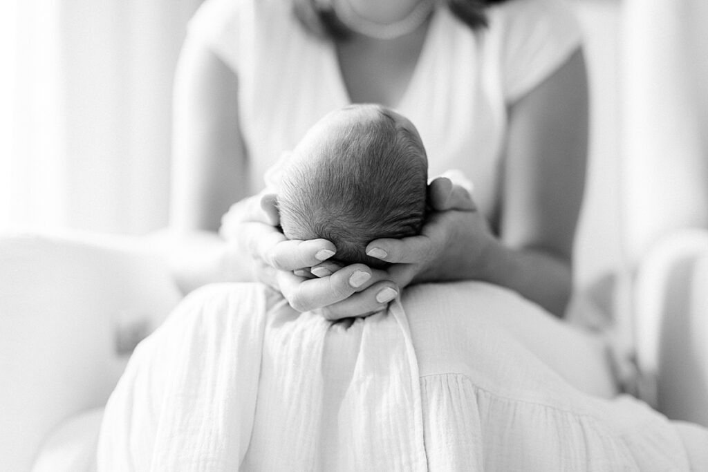 A mother holding her newborn in a black and white photo by newborn photographer Katelyn Ng