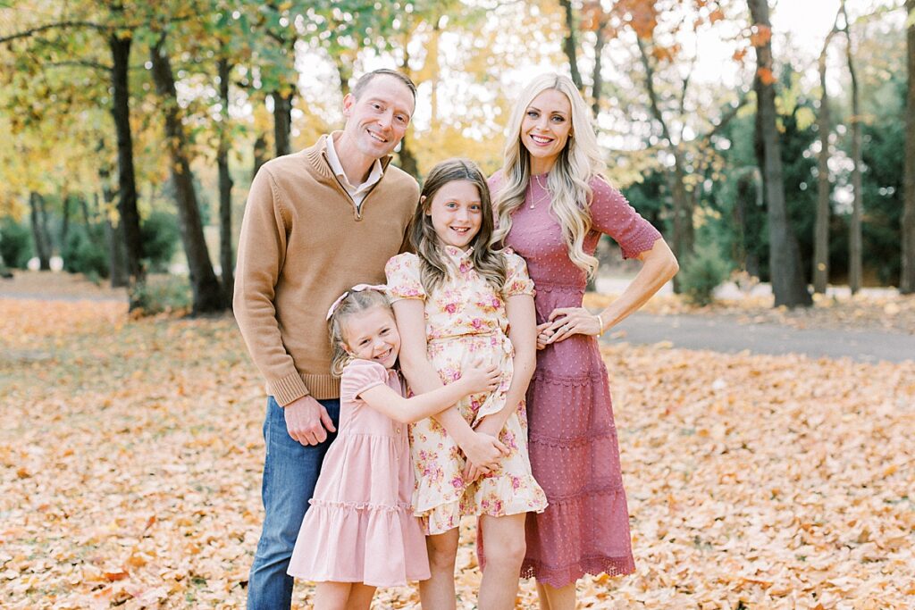 A Carmel Indiana family stands outdoors amid autumn leaves in their fall family photos.