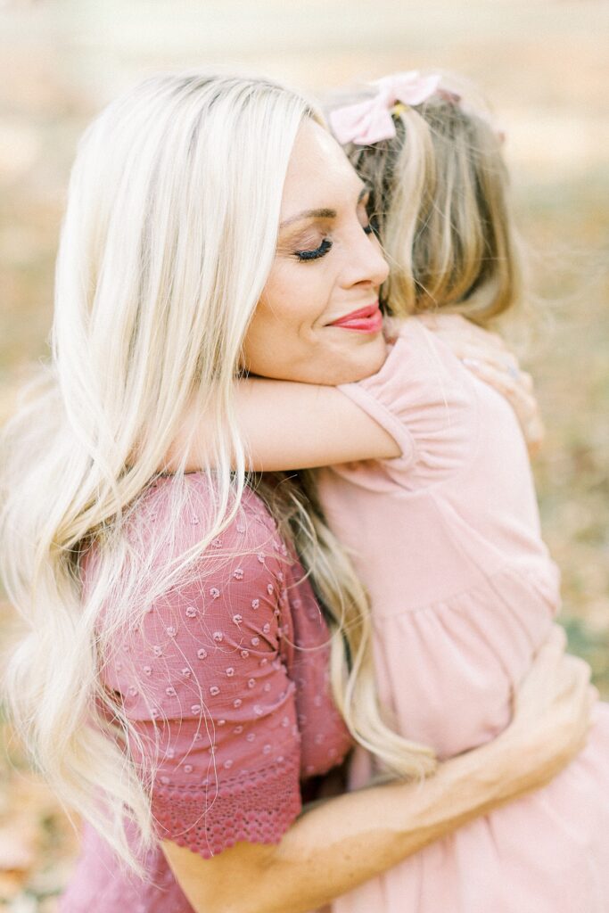 A mom hugs her young daughter during their Carmel, Indiana fall family photo session by Katelyn Ng Photography.
