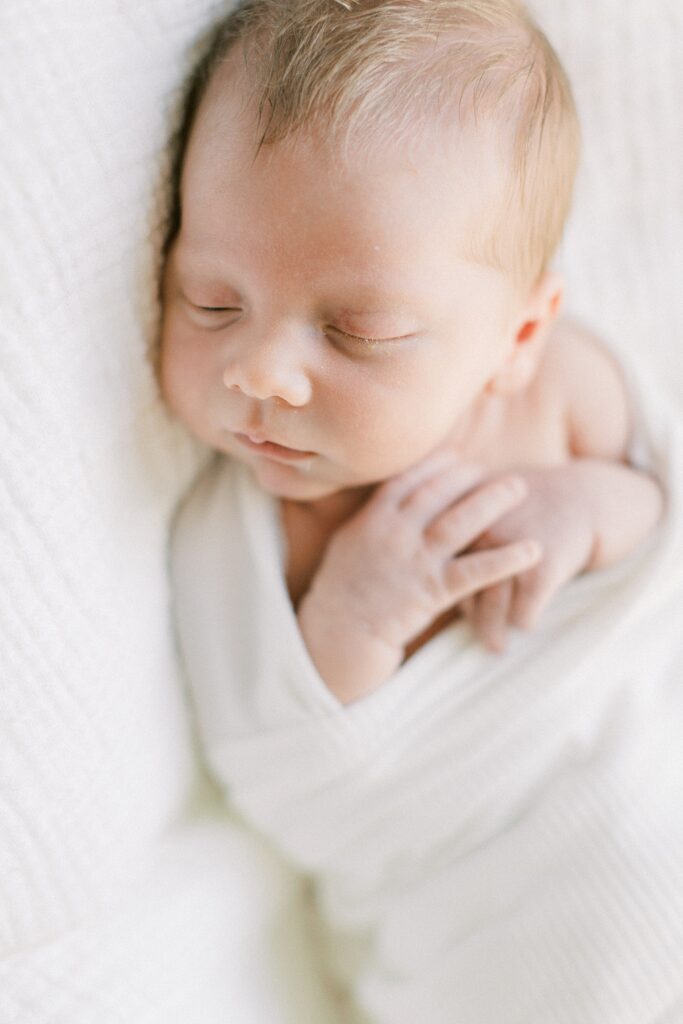 A newborn photo of a baby boy laying on a white blanket by Indianapolis Photographer Katelyn Ng Photography.