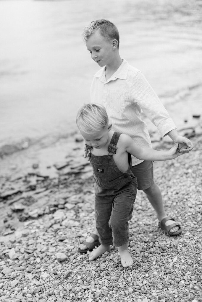 A black and white photo of two brothers walking along a beach together in Bloomington Indiana by family photographer Katelyn Ng Photography.