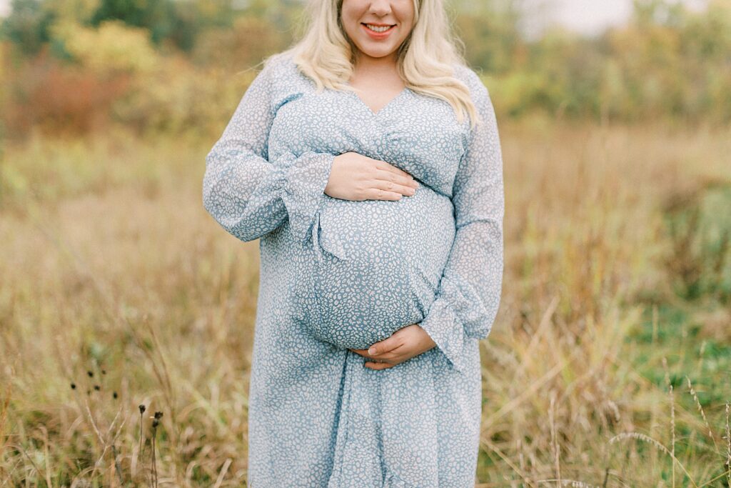 A woman holds her belly and poses for a maternity photo by Katelyn Ng Photography.