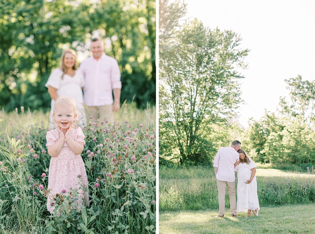 A little girl stands amid wildflowers while her parents look on in the background behind her.