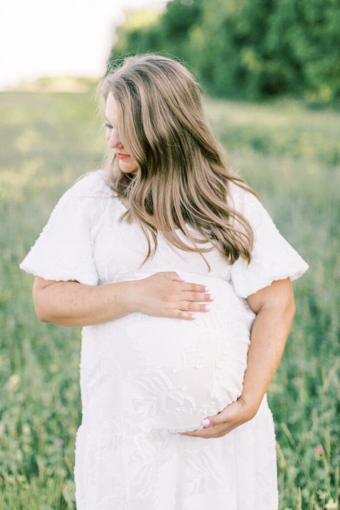 A pregnant woman with long brown hair poses for a photo by one of Indianapolis family photographers, Katelyn Ng.