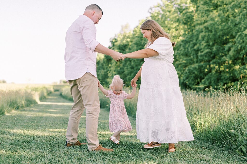 A family plays together in a field during their session with one of Indianapolis family photographers.