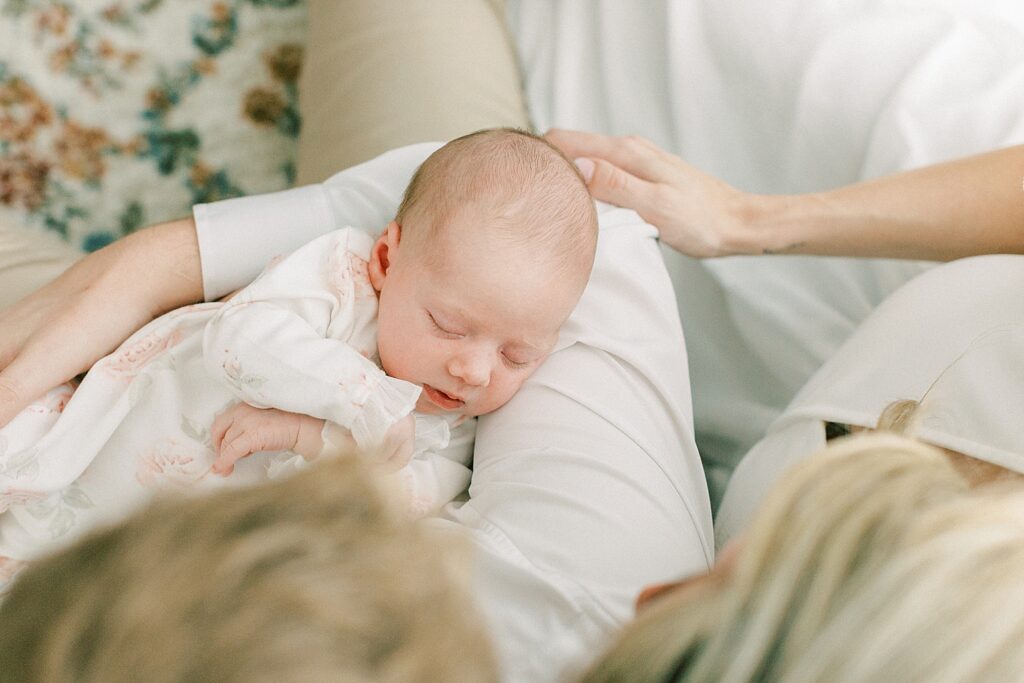 A little girl sleeps in her parents arms in her nursery.