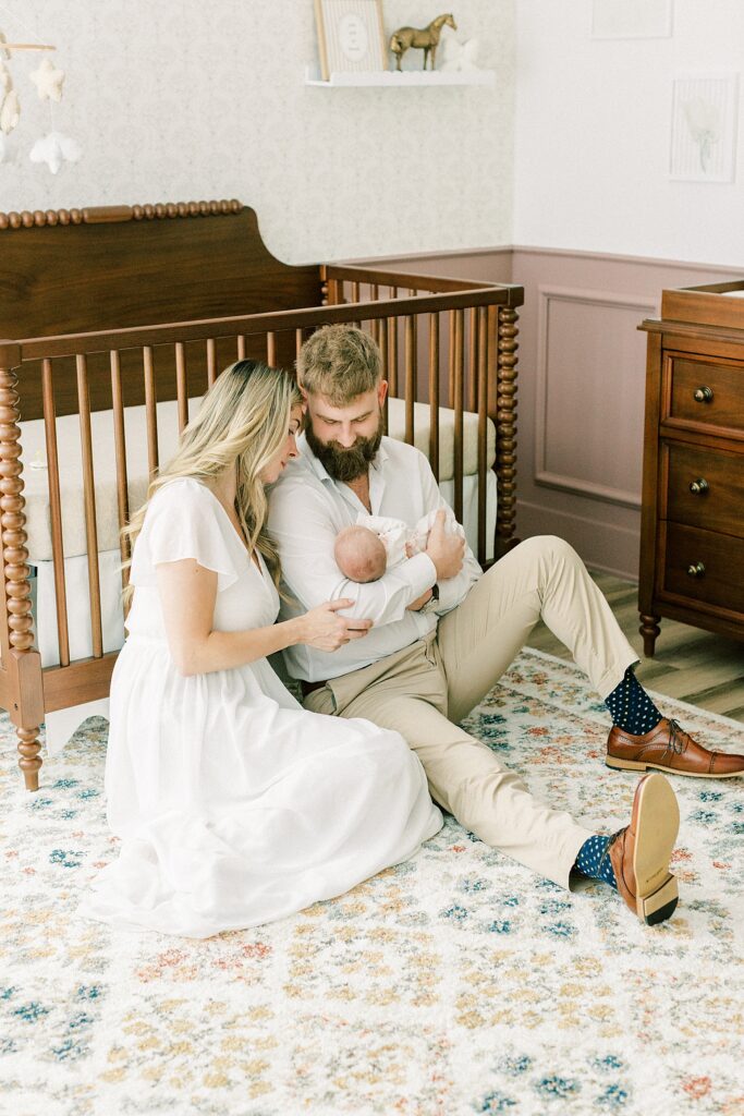 A father and mother sit on the floor of their daughter's nursery as Katelyn Ng takes their newborn photos in Indianapolis.