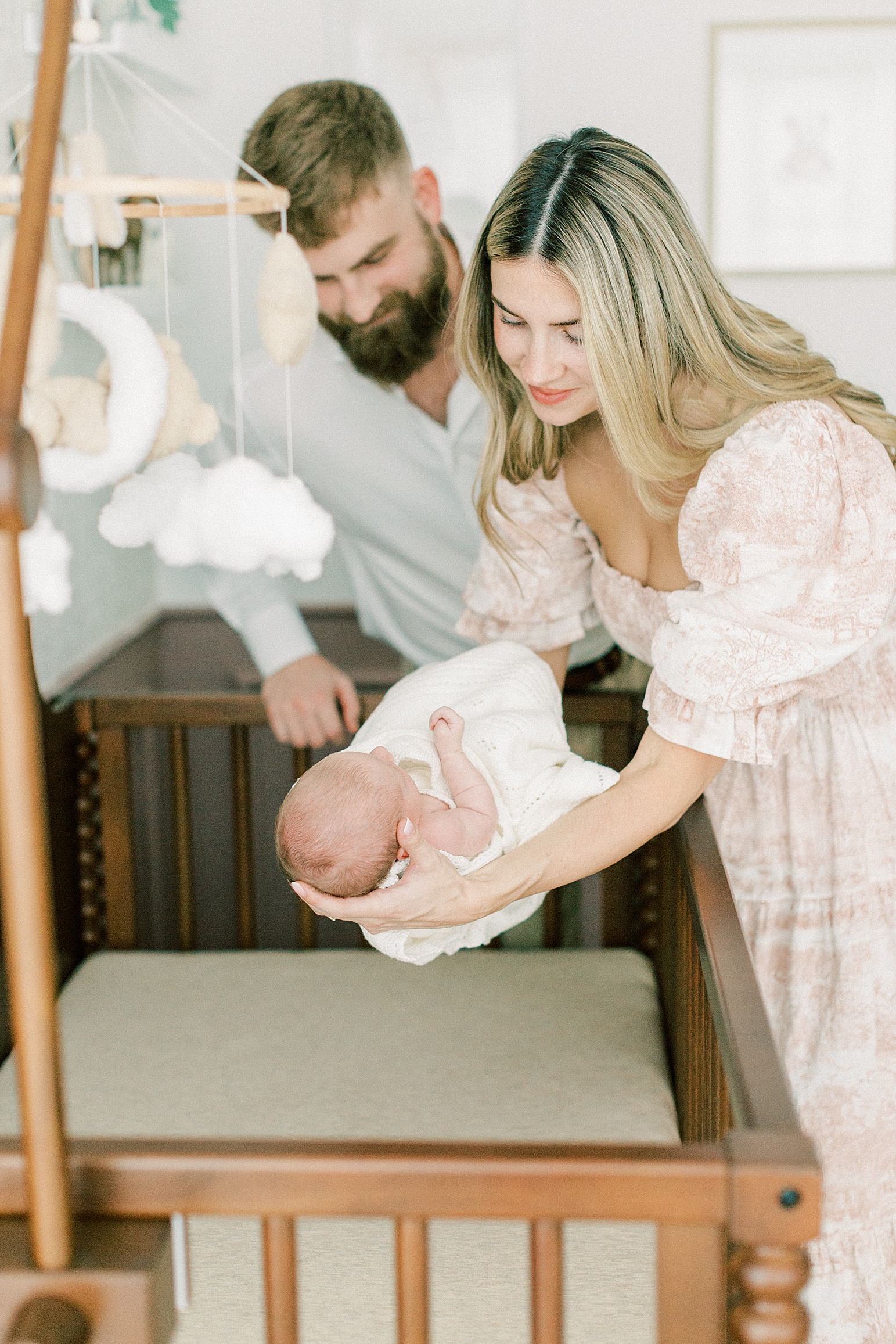 A mother and father gently lay their newborn daughter into her crib during their newborn photos in Indianapolis